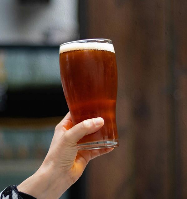 Hand holding Ales in a pint - Champers Drinks
