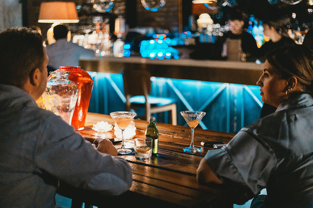 a-couple-drinking-martini-on-a-wood-table - Champers Drinks
